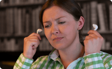 Kvinna som använder hörlurar i behov av Otinova öronspray.
